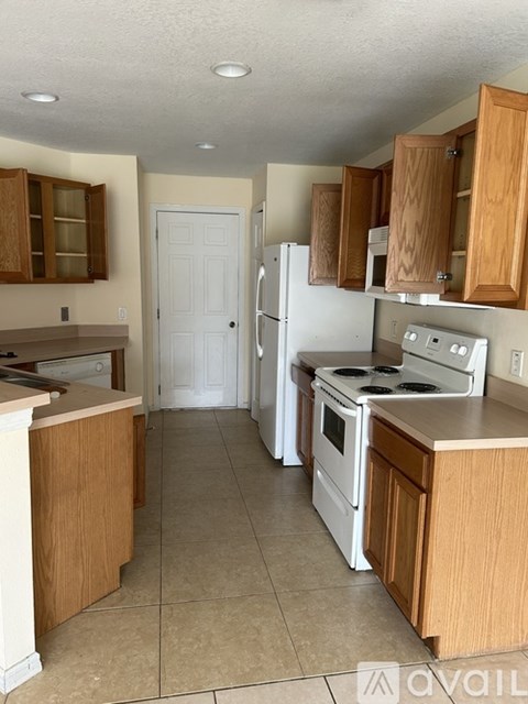 A kitchen with white appliances and wooden cabinets.