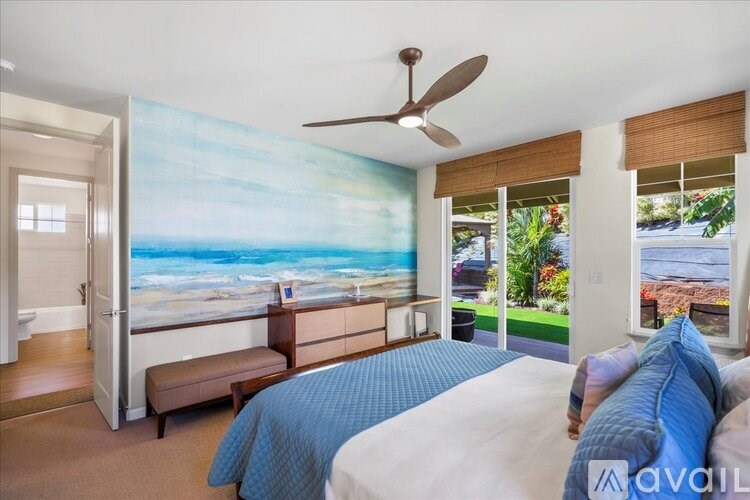 A bedroom with a large bed and a painting of a beach scene on the wall.