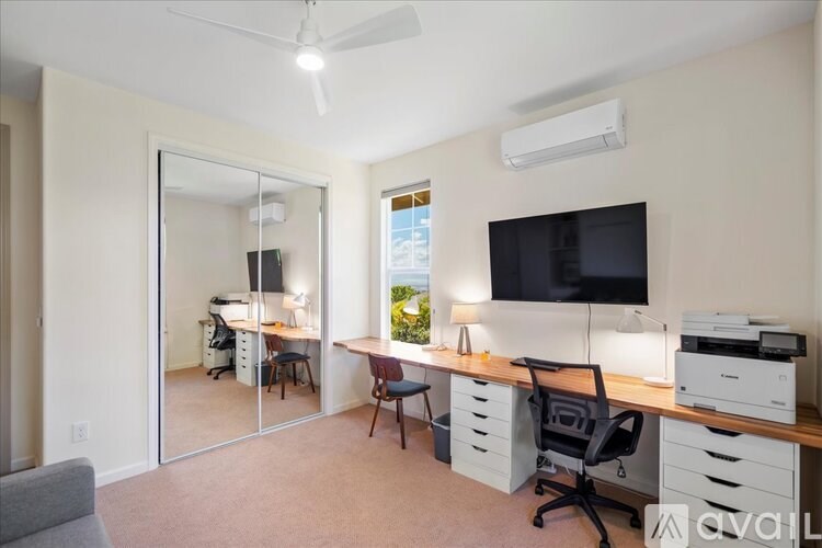 A well-lit office space with a desk, chairs, and a television.