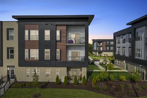 A modern apartment building with a well-maintained garden in front.