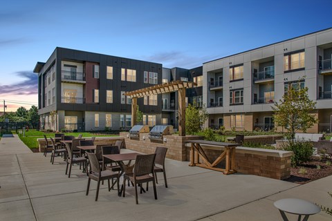 A modern apartment complex with a patio area and outdoor furniture.