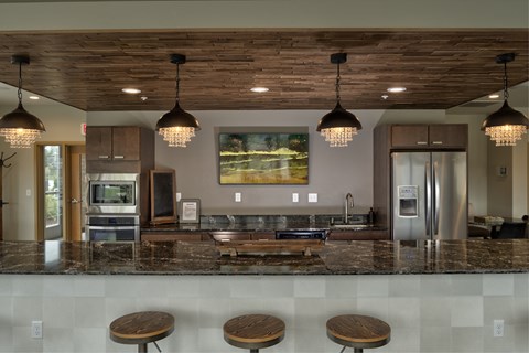 A kitchen with a marble counter top and wooden bar stools.