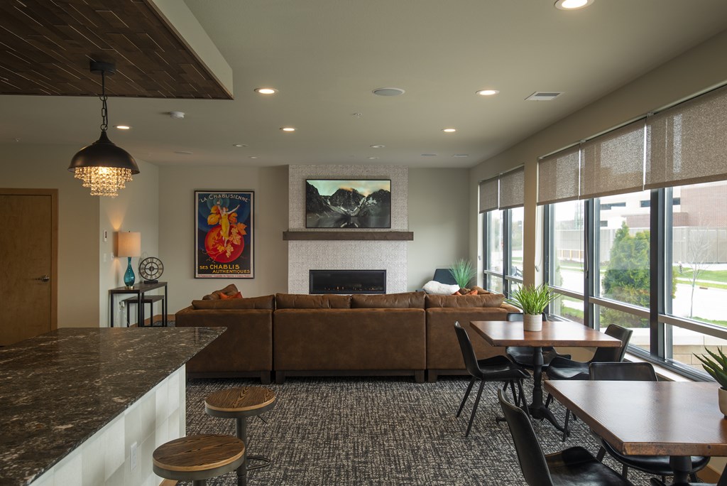 A modern living room with a fireplace and a painting of a sunset.