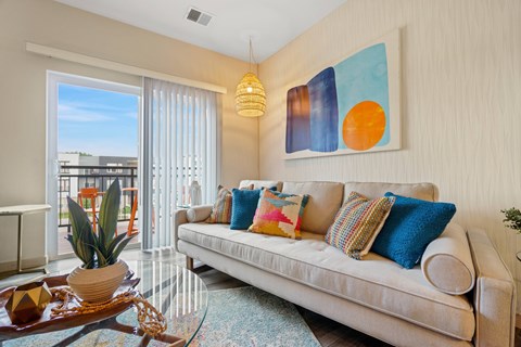A living room with a couch, a table, and a painting on the wall.