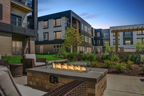 A modern apartment complex with a fire pit in the foreground.