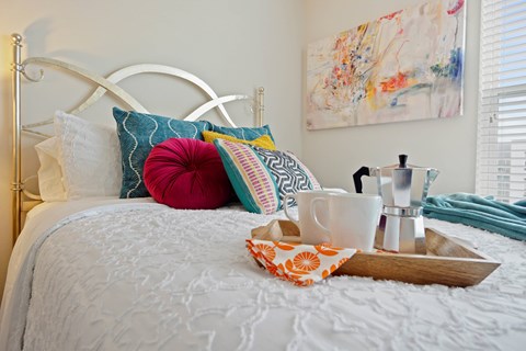 A white bed with a tray of items on it.