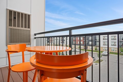 A balcony with a table and chairs overlooking a street.