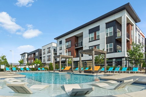 A large swimming pool in front of a multi-story apartment building.
