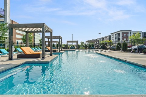 A large swimming pool with a wooden pergola and lounge chairs.