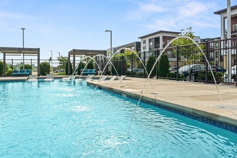 A swimming pool with a metal fence and a building in the background.