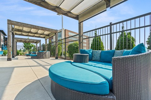 A patio with a blue cushioned chair and a wicker table.