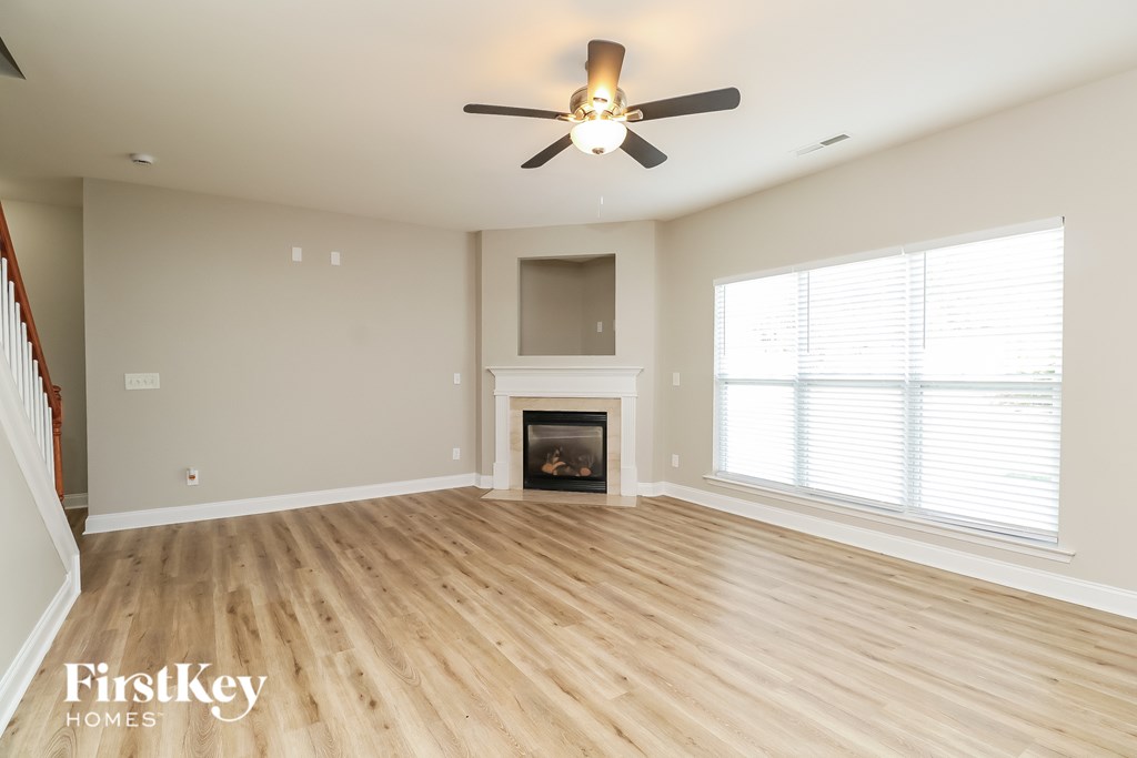 A spacious room with a fireplace and a ceiling fan.