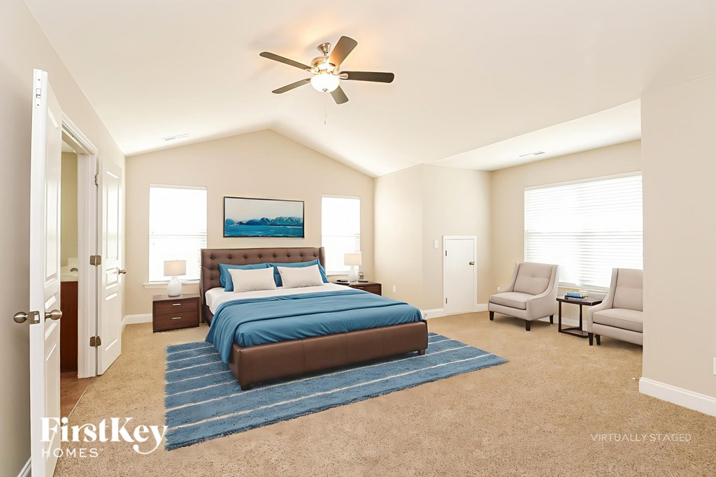 A bedroom with a bed, two chairs, and a ceiling fan.