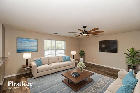 A living room with a beige couch, a coffee table, and a ceiling fan.