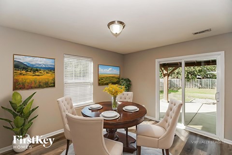 A dining room with a table set for two and a painting of a mountain scene on the wall.