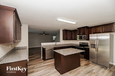 A kitchen with brown cabinets and a FirstKey Homes logo.
