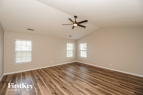 A spacious room with wooden flooring and a ceiling fan.