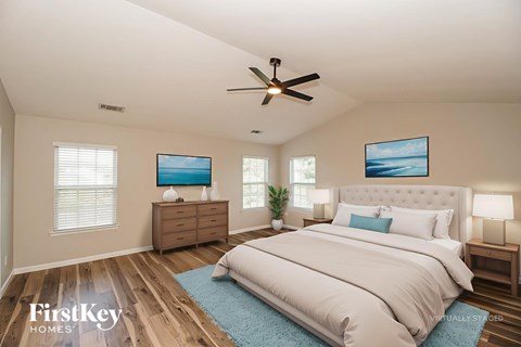 A bedroom with a large bed, a ceiling fan, and two picture frames on the wall.