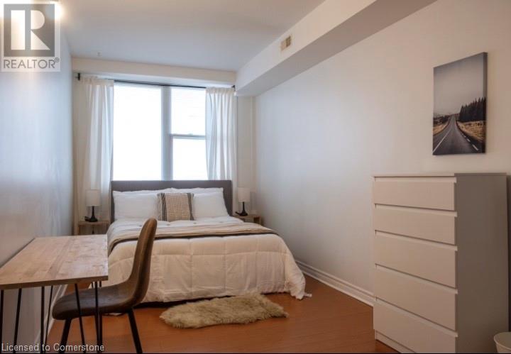 A bedroom with a bed, chair, and a painting on the wall.