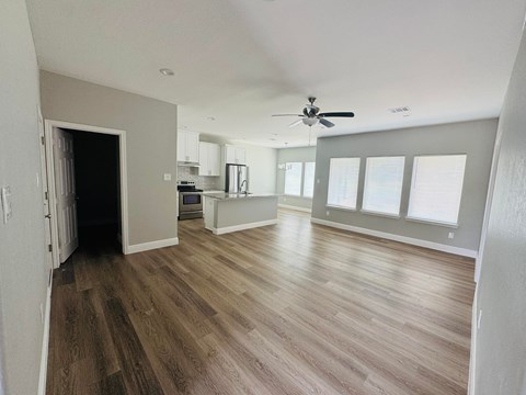 A spacious room with wood flooring and a ceiling fan.