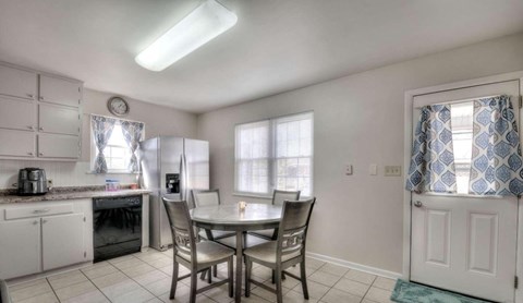 A kitchen with a table and chairs in front of a window.