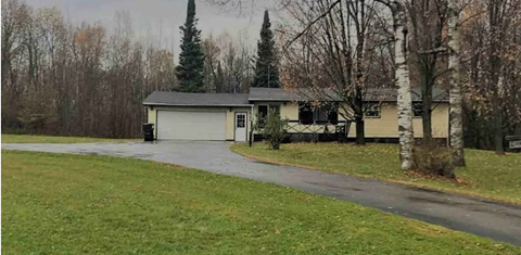 A house with a driveway and trees in the background.