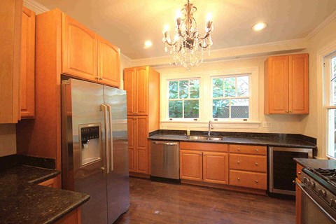 A kitchen with wooden cabinets and a chandelier.