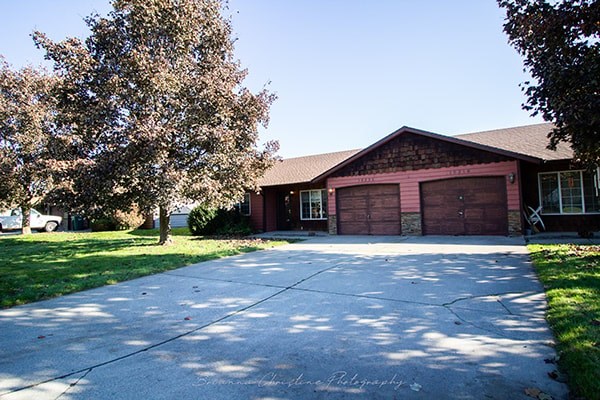 A house with a red garage door is surrounded by trees.