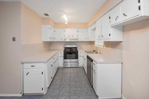 A kitchen with white cabinets and appliances.