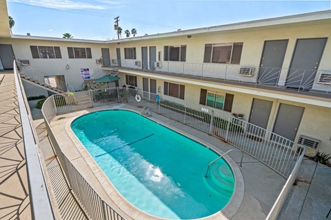 A swimming pool in a courtyard surrounded by a metal fence.