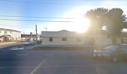 A sunny day in a parking lot with a white building and a tree.