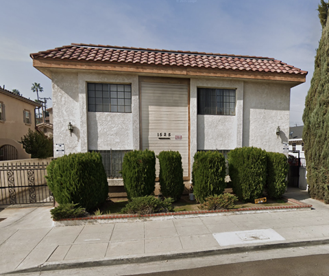 A house with a red tile roof and white walls with a brown door and windows.