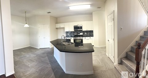 A kitchen with a black countertop and a stove top oven.