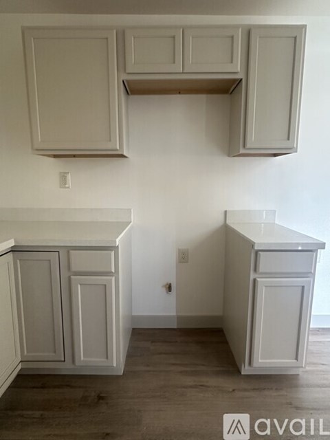 A kitchen with white cabinets and a wooden floor.