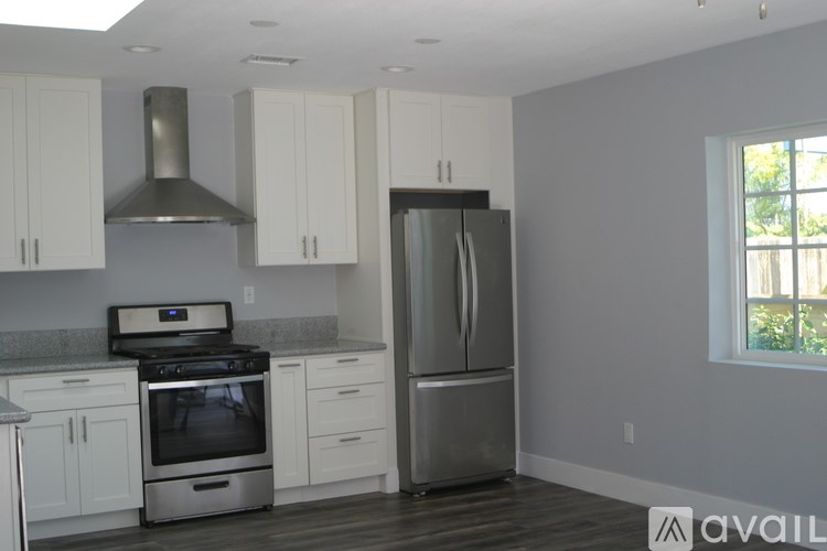 A kitchen with white cabinets and a stainless steel refrigerator.
