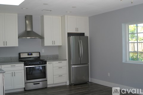 A kitchen with white cabinets and a stainless steel refrigerator.