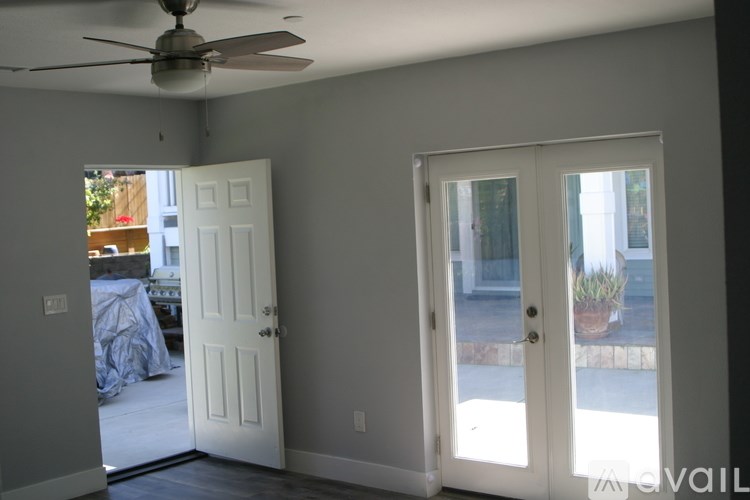 A room with a ceiling fan and two doors, one of which is open.