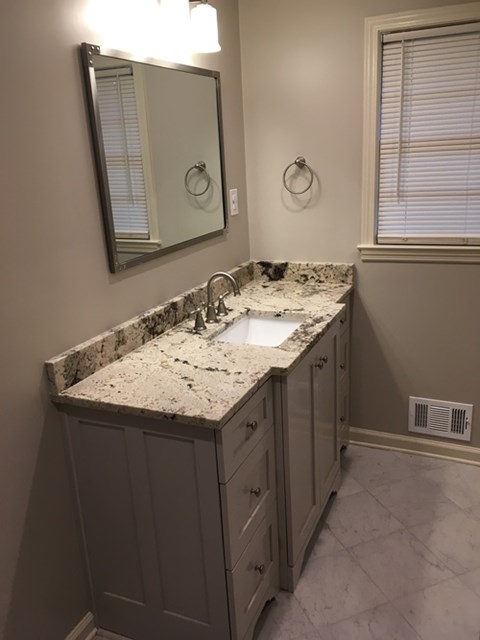 A bathroom with a marble countertop and a large mirror.