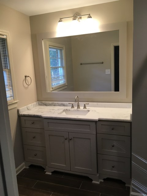 A bathroom with a sink, mirror, and cabinets.