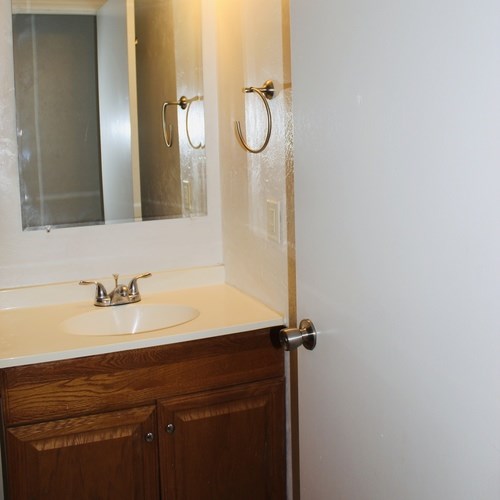 A white sink with a wooden cabinet and a mirror above it.