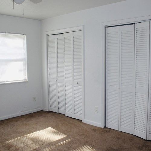 A room with white walls and a window with white blinds.