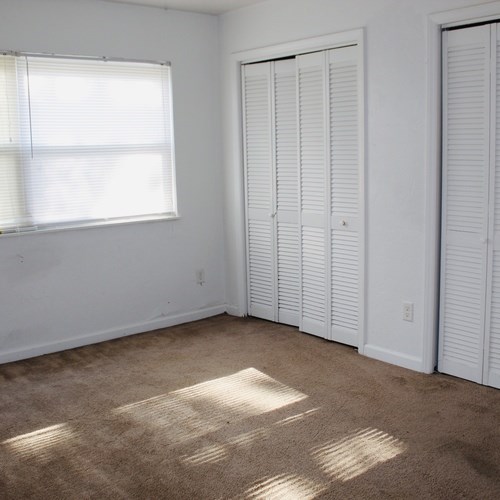 A room with white walls and a window with blinds.