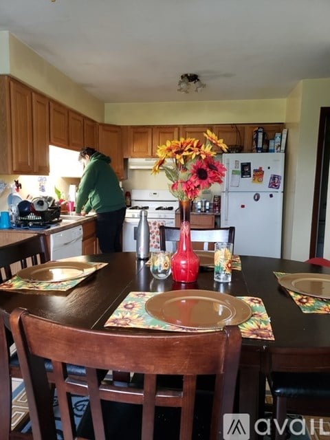 A woman is standing in a kitchen with a table set for a meal.