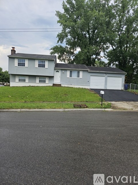 A two-story house with a garage is situated on a street with a grassy area in front.