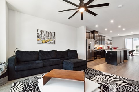 A black couch sits in a living room with a wooden coffee table in front of it.