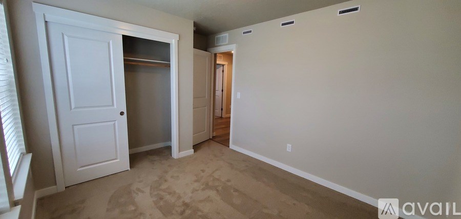 A bedroom with a white door and a carpeted floor.