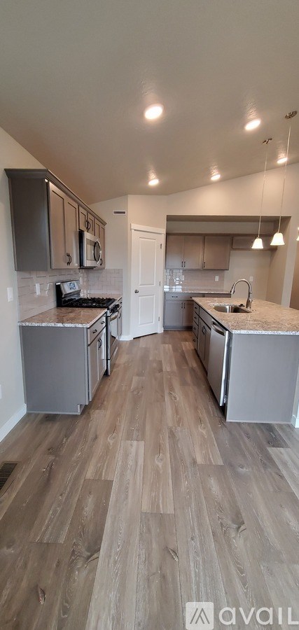 A kitchen with wooden flooring and modern appliances.