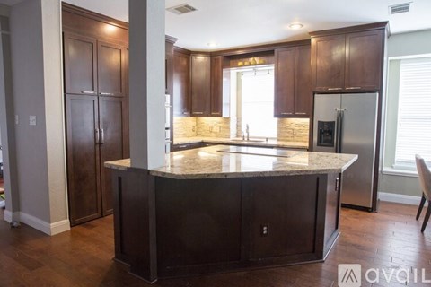 A kitchen with dark wood cabinets and a granite countertop.