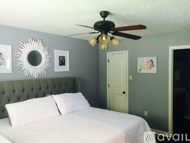 A bedroom with a bed, a ceiling fan, and a mirror on the wall.