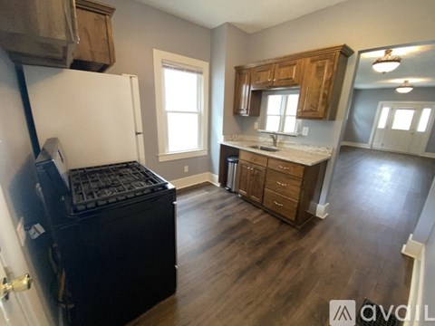 A kitchen with a black stove top oven and wooden cabinets.
